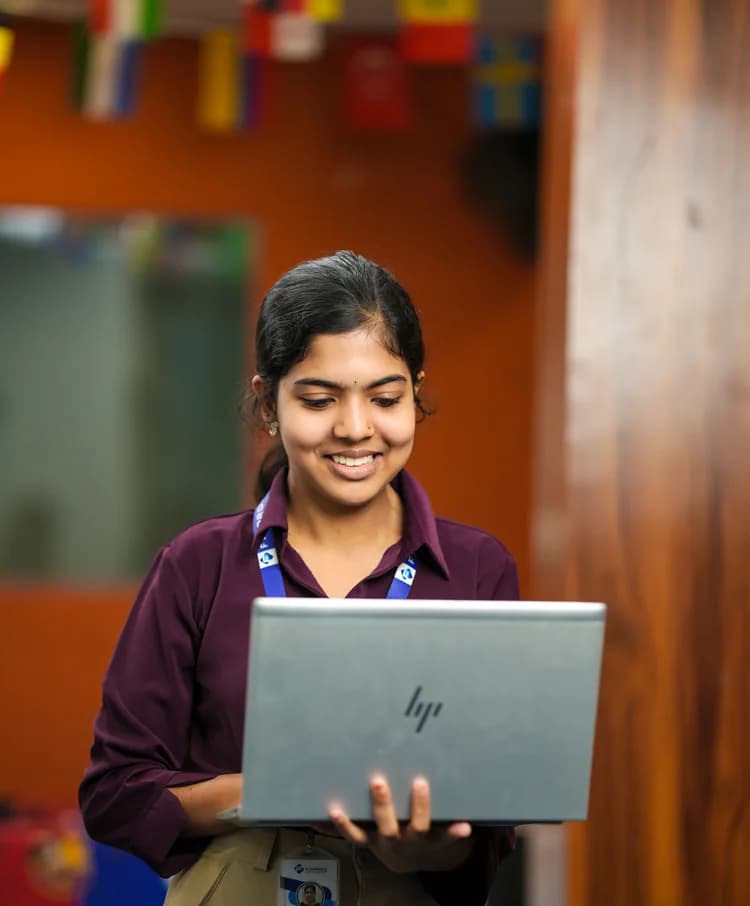A Finprov student smiling at her laptop on campus
